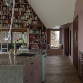 Cuisine Ateliers Jacob avec îlot en quartzite pleine hauteur, armoires rose bordeaux et bibliothèque sur mesure intégrée dans une aire ouverte lumineuse au design contemporain haut de gamme.
