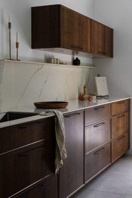 Cuisine haut de gamme Ateliers Jacob avec deux îlots en Dekton effet marbre, armoires en noyer foncé et grande fenestration ouverte sur la nature.