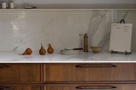 Détail d’un comptoir et dosseret en Dekton dans une cuisine Ateliers Jacob, avec armoires en bois foncé et accessoires décoratifs minimalistes.