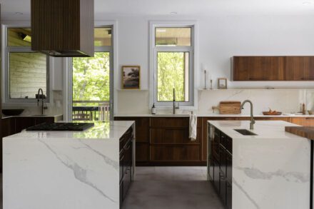 Cuisine sur mesure Ateliers Jacob avec armoires en noyer foncé, comptoir en Dekton effet pierre naturelle et lignes épurées inspirées du design contemporain.