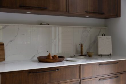 Cuisine sur mesure Ateliers Jacob avec armoires en noyer foncé, comptoir en Dekton effet pierre naturelle et lignes épurées inspirées du design contemporain.