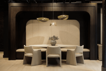 Dining nook by Ateliers Jacob: banquette set in a dark wood arch, oval table and sculptural brass pendants create a cozy, elegant space.