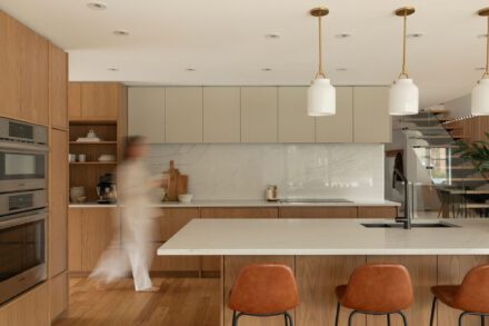 Cuisine contemporaine Ateliers Jacob en chêne avec grand îlot en quartz, armoires deux tons, dosseret en quartz effet marbre et luminaires suspendus.