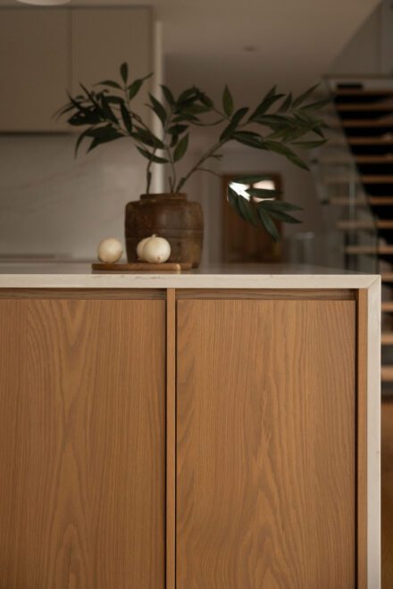 Détail du grand îlot de cuisine Ateliers Jacob en chêne avec comptoir de quartz à effet cascade, mettant en valeur les veinures du bois et les lignes épurées du mobilier.